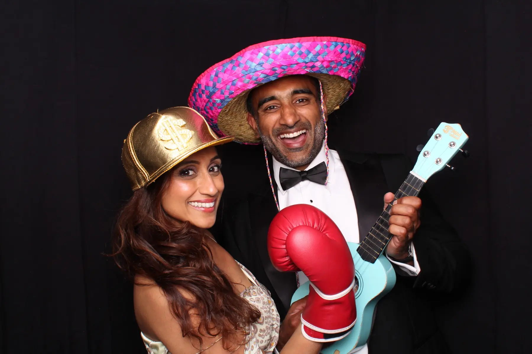 A wedding couple laughing with colourful photo booth props